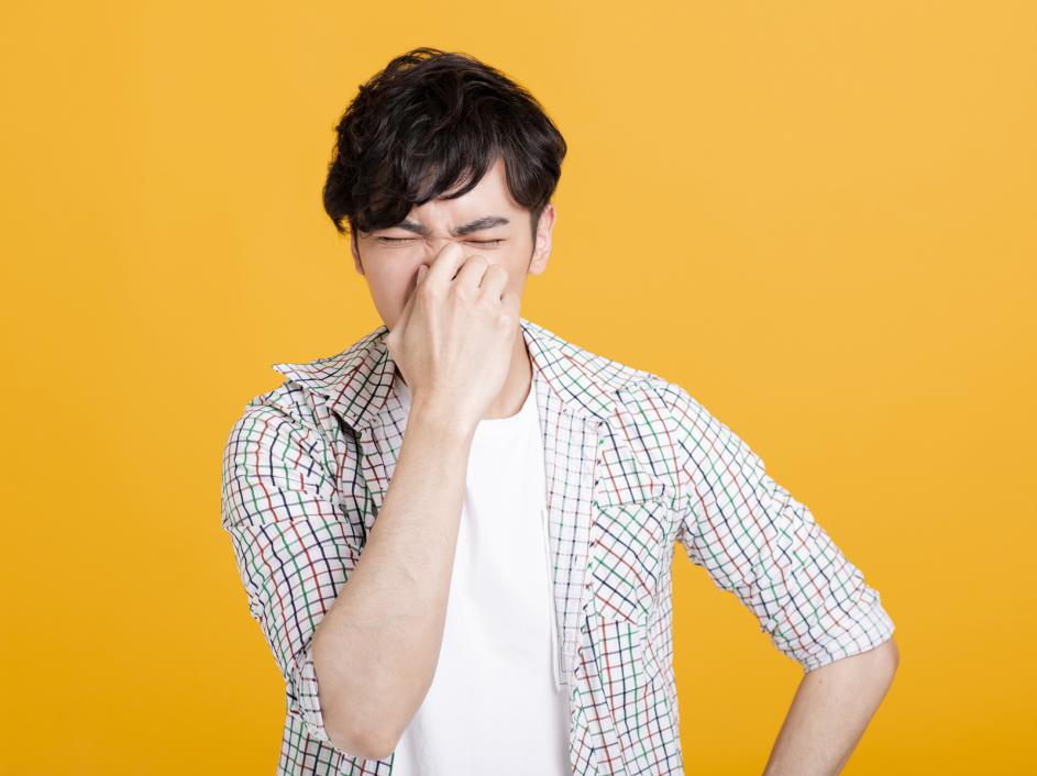 An Asian man pinching his nose because the toilet releases an unpleasant smell.